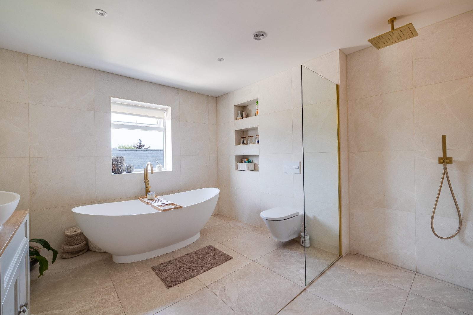 Bright family bathroom with freestanding stone bath, walk-in shower and porcelain tiling