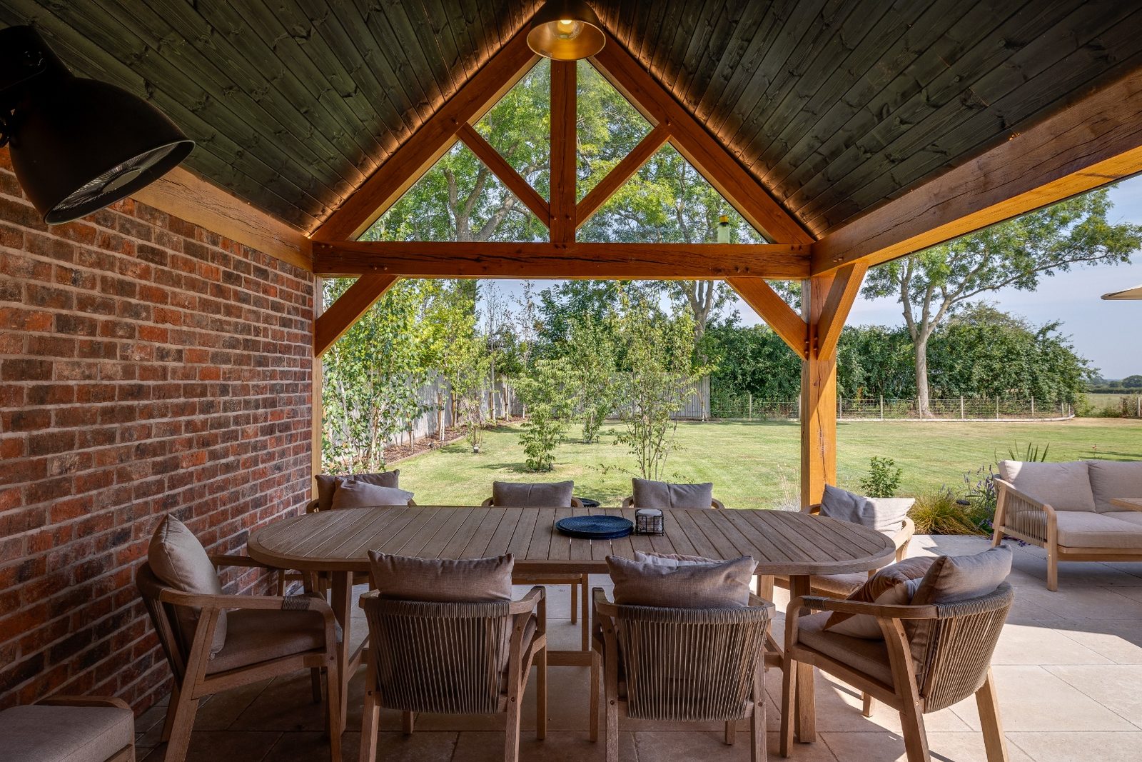 Interior of an oakframe garden pavilion looking out through timber trusses to open countryside