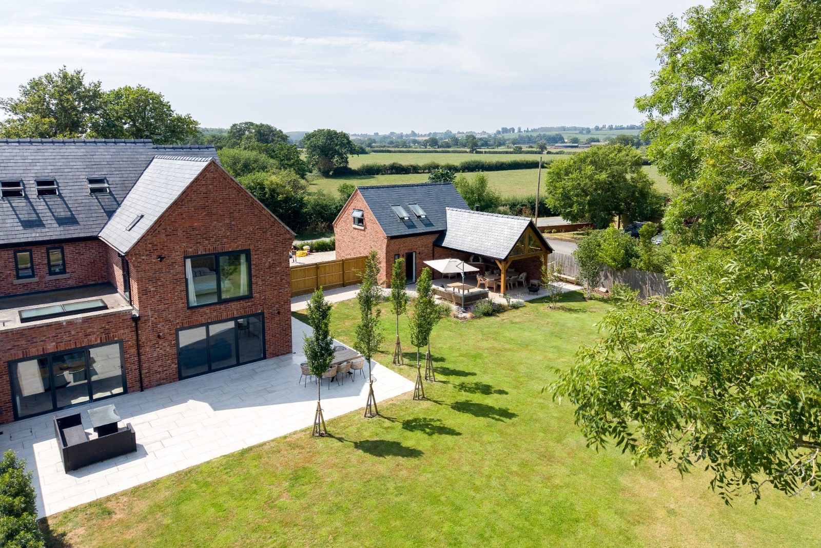 Aerial view of a completed residential renovation with slate roofs and oakframe outdoor pavilion