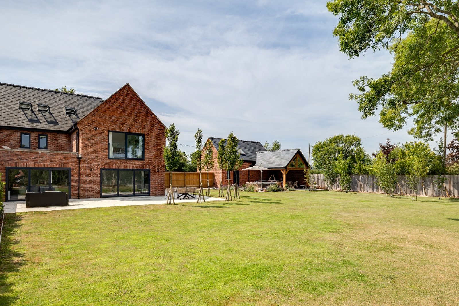 Rear elevation of a completed brick residential renovation with slate roof and landscaped garden