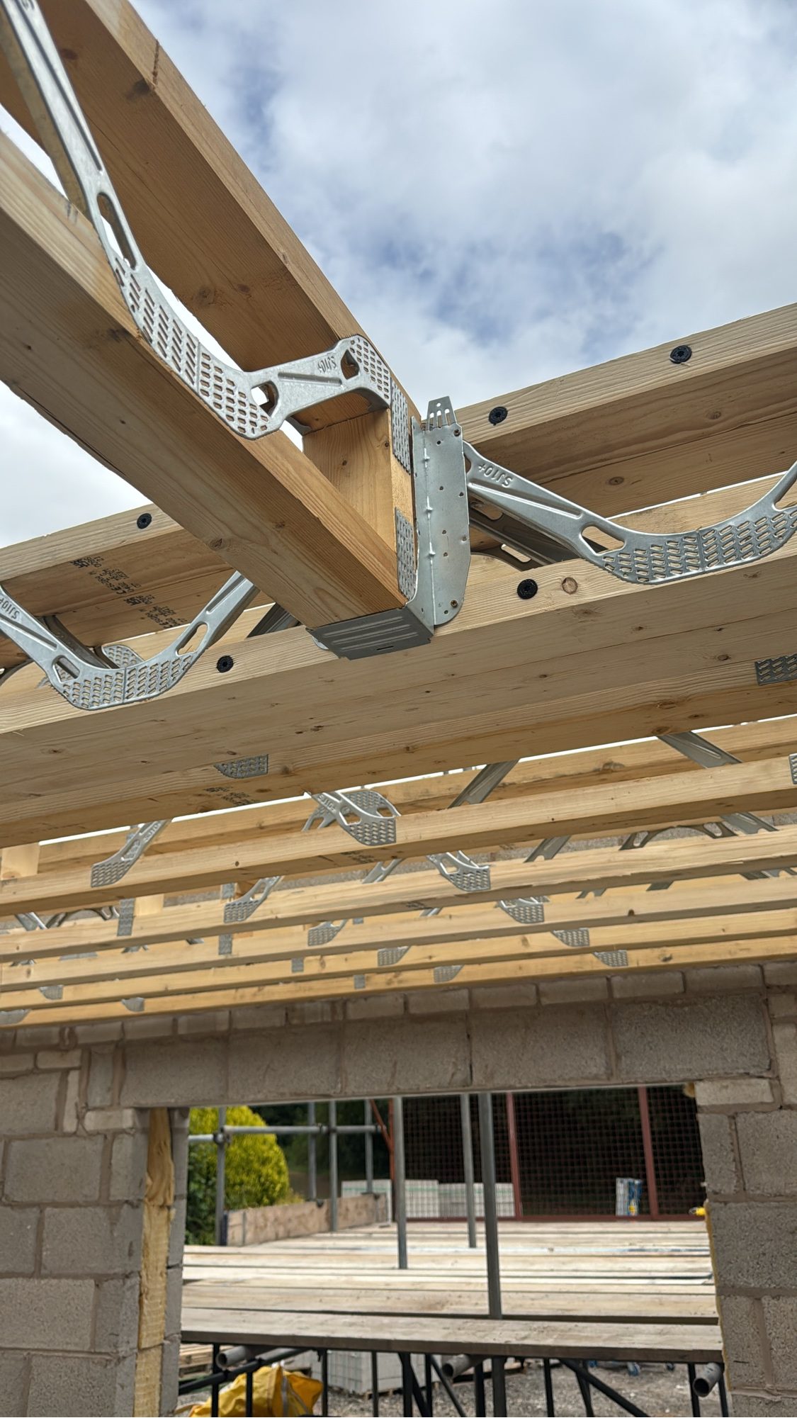Close-up of galvanised joist hangers and structural timber on a live Built Clear build